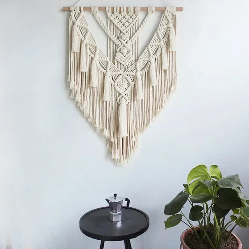 Cream-colored macrame wall hanging with intricate woven patterns and long fringe tassels perfect for chic bohemian decor