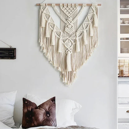 Cream-colored macrame wall hanging with intricate woven patterns and long fringe tassels for chic bohemian decor