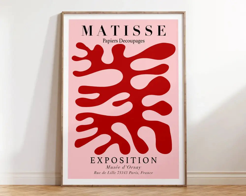 A framed matisse floral print with bold red abstract shapes on soft pink background in a minimalist wooden frame