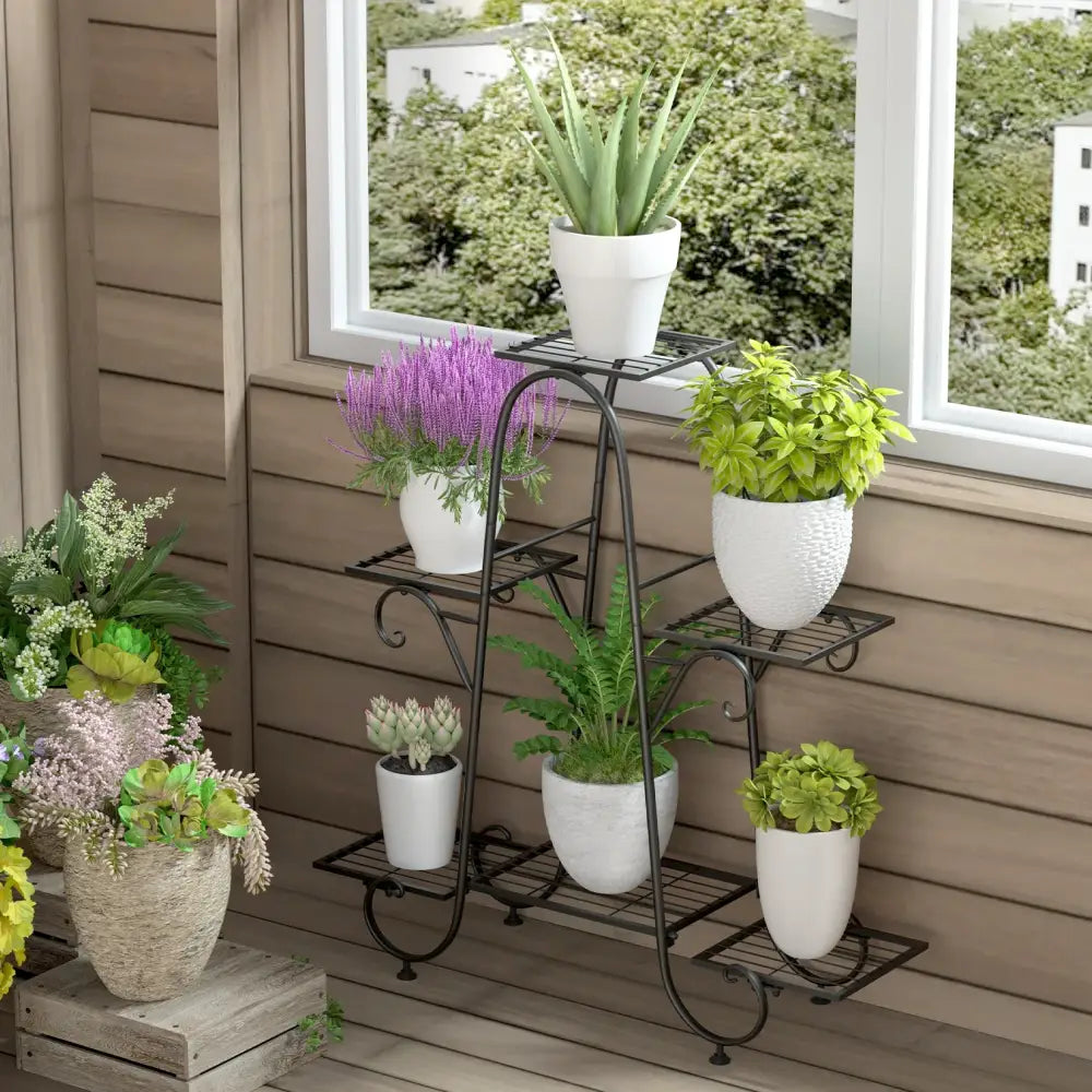 Black wrought iron metal plant stand with curved legs and six tiers holding white ceramic pots by DecorBites