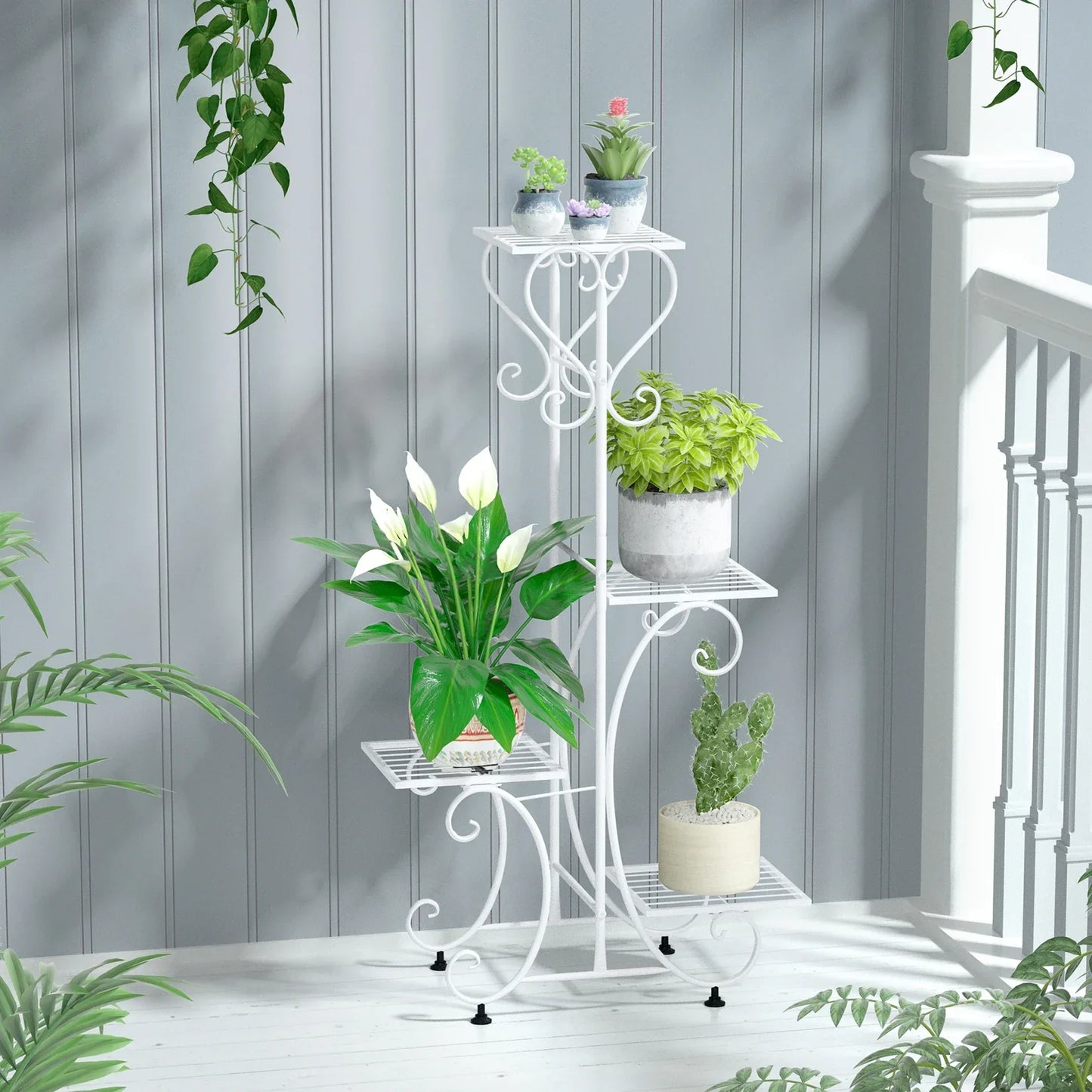 White wrought iron metal plant stand with ornate scrollwork and four tiers for holding flower pots by DecorBites