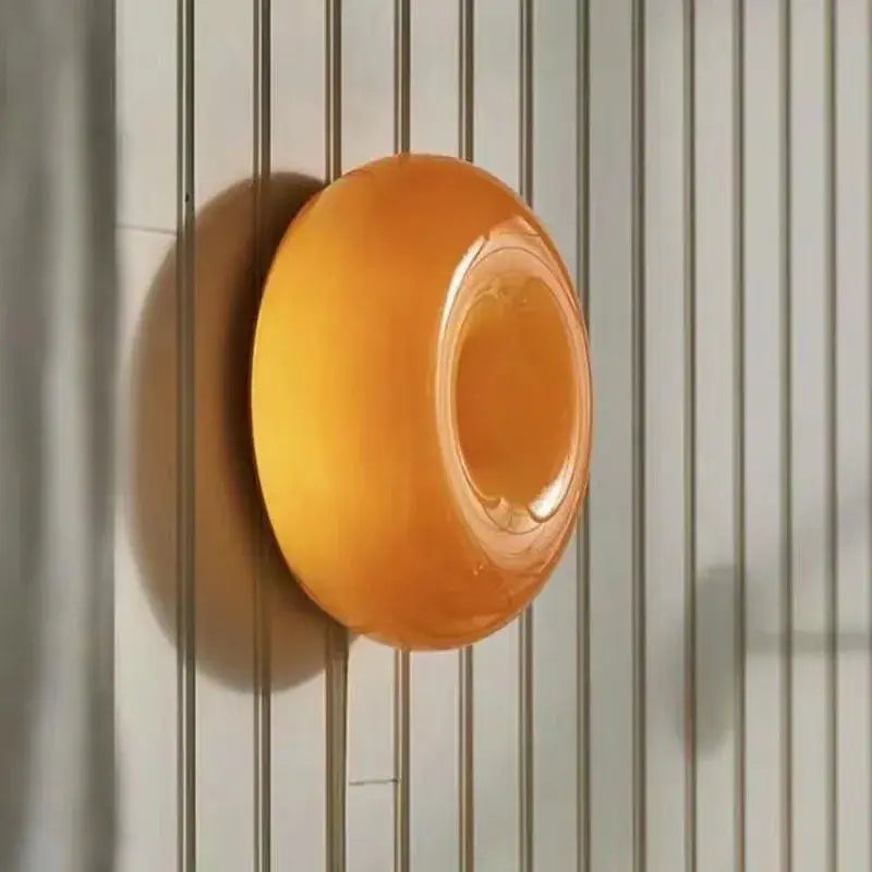 A translucent orange circular soap dish with a smooth glossy finish complementing a modern desk lamp setup