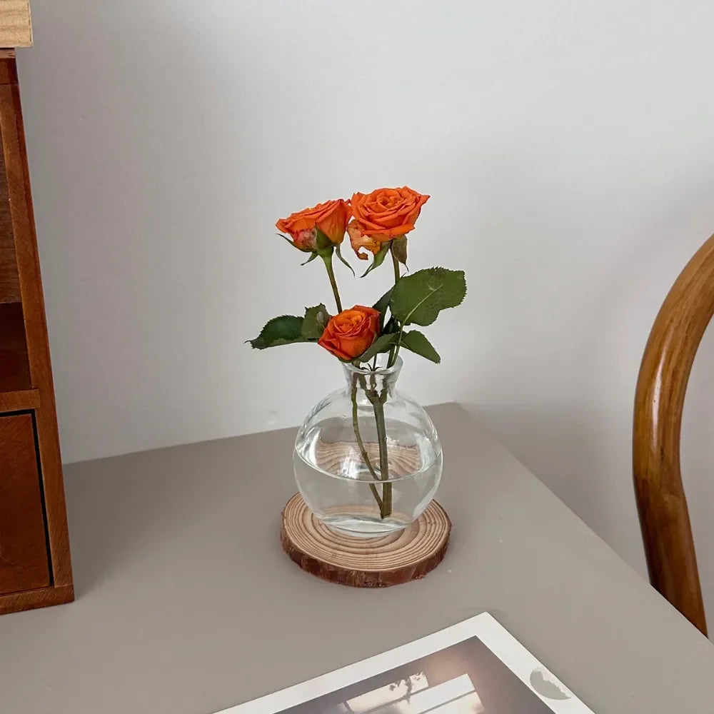 Decorbites™ mini clear glass flower vase with rounded body and narrow neck holding three vibrant orange roses for home decor