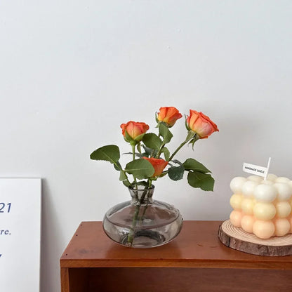DecorBites™ mini glass flower vase with rounded base and narrow neck holding orange roses for home decor