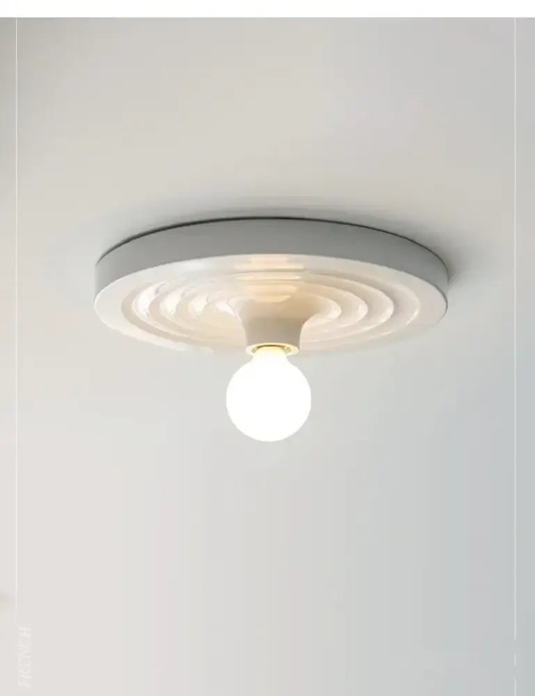 A modern matte white circular decorbites bauhaus lamp with concentric ridges as a minimalist ceiling light fixture