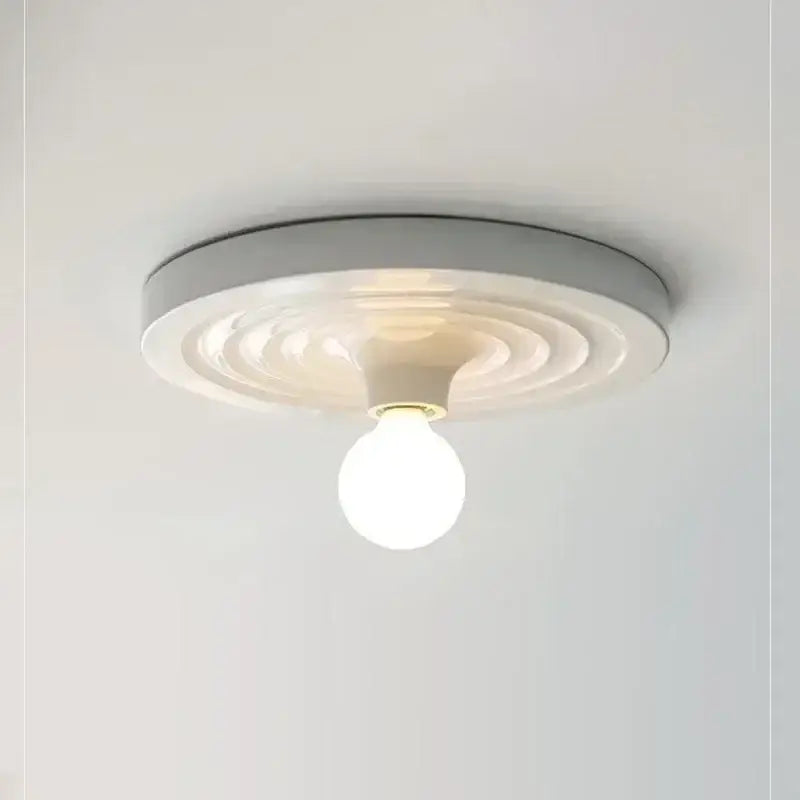 A modern white ceiling-mounted decorbites bauhaus lamp featuring concentric circular ridges and a central bulb
