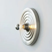 A decorbites bauhaus lamp featuring a minimalist wall-mounted design with brushed metallic concentric rings and clear glass bulb