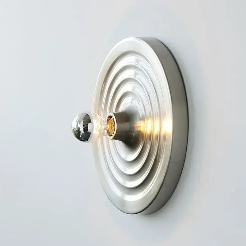 A decorbites bauhaus lamp featuring a minimalist wall-mounted design with brushed metallic concentric rings and clear glass bulb