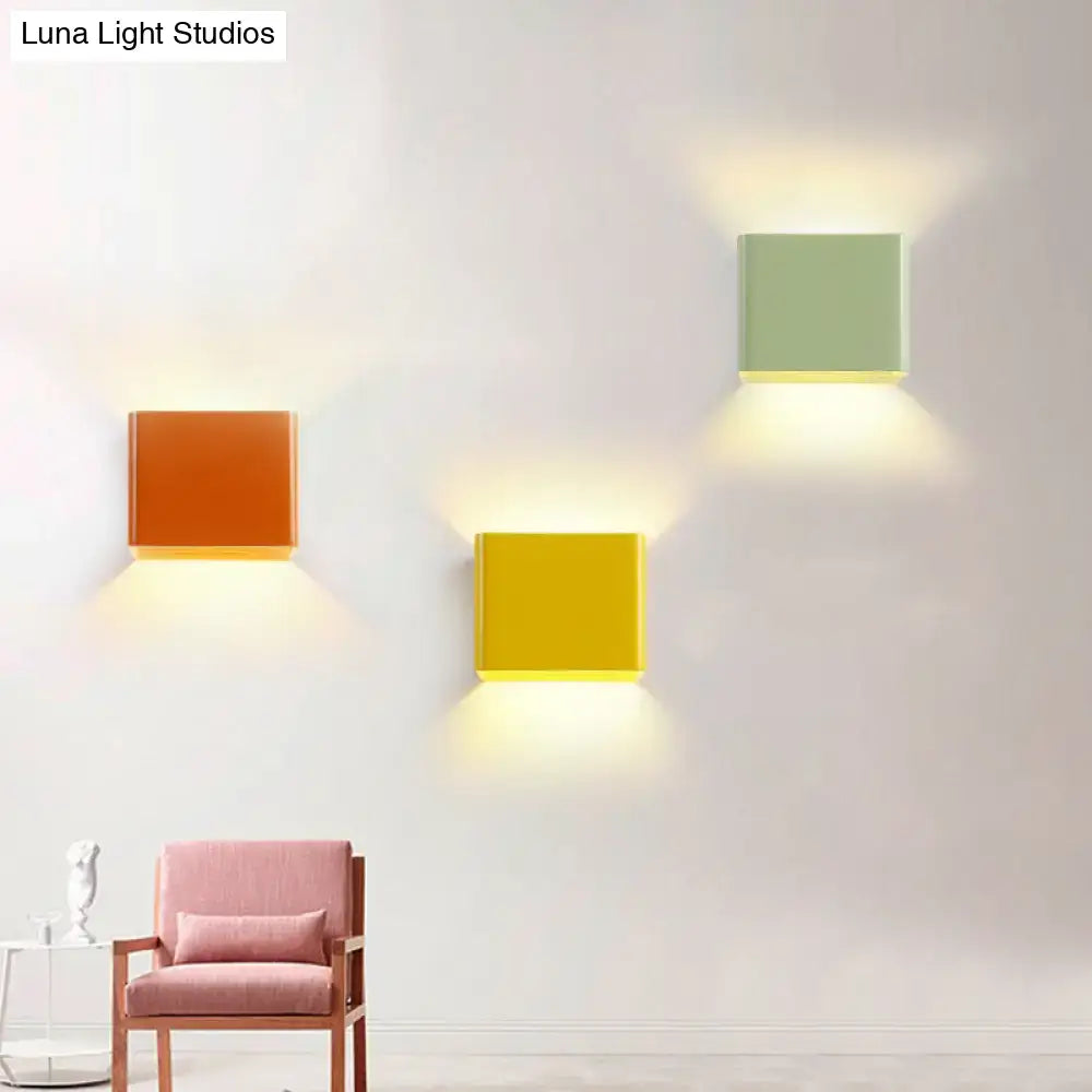 Three square orange yellow and sage green decorbites minimalist cube shade sconce lights emit warm glow in living room