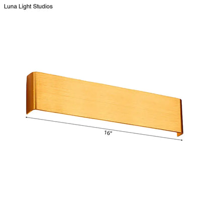 A sleek brushed gold 16-inch rectangular wall lamp with warm white light for minimalist living room decor