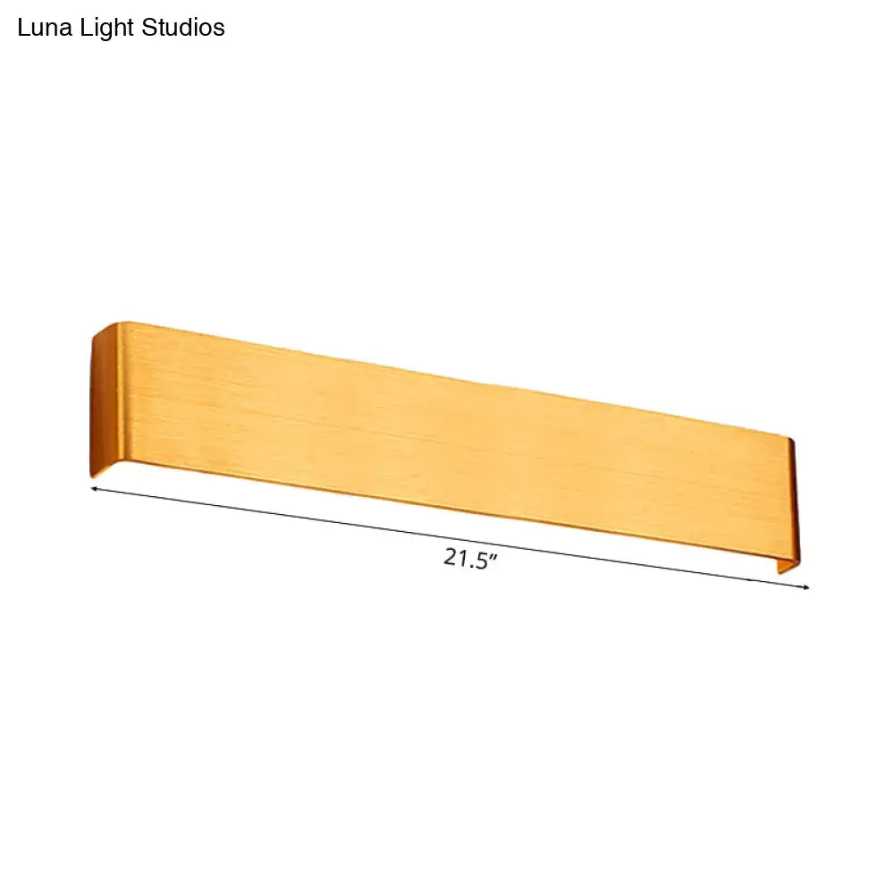 A sleek brushed gold rectangular wall lamp with modern design and warm white light for living room use