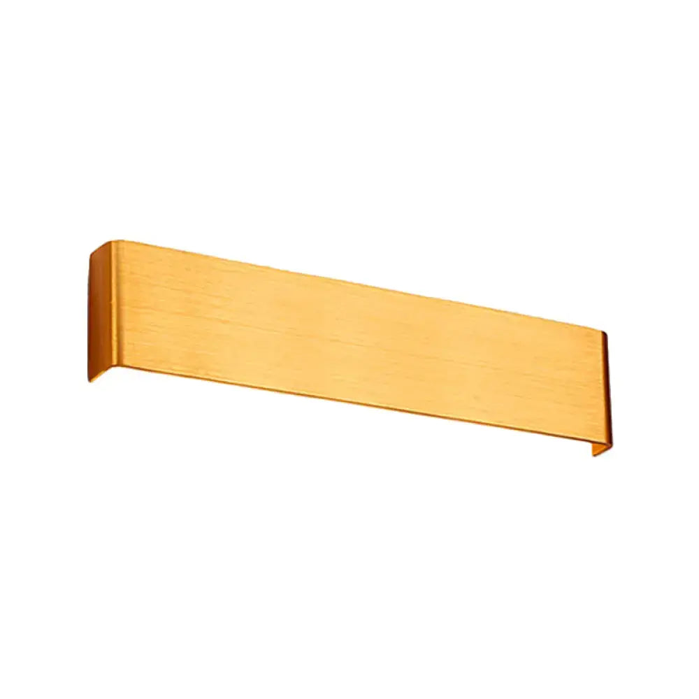 Gold-colored brushed metal wall lamp with sleek rectangular design providing warm white light for living room use