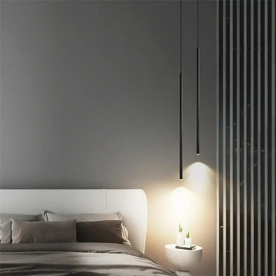 Two sleek black cylindrical decorbites™ modern 2cm led pendant lights casting warm glow over bedside table