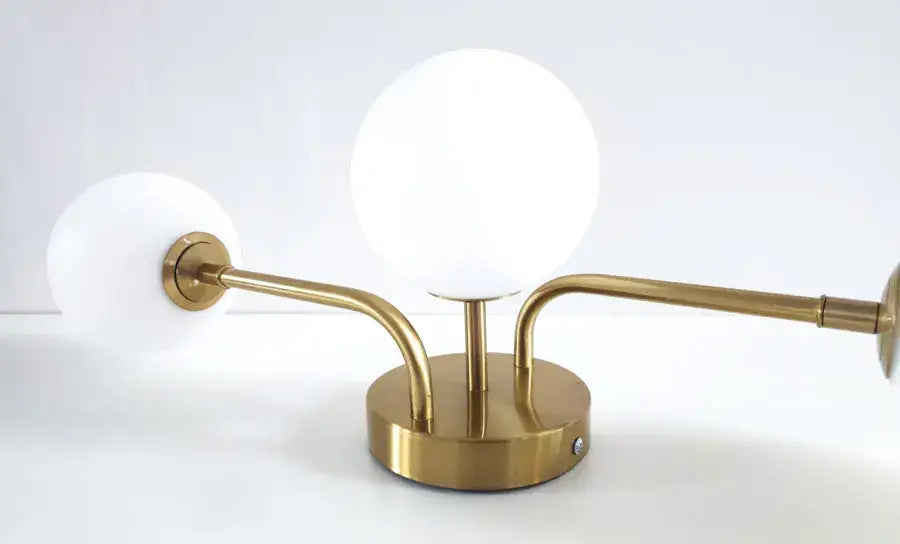 Gold-toned table lamp with three frosted glass globe shades and curved metal arms for modern ceiling light décor