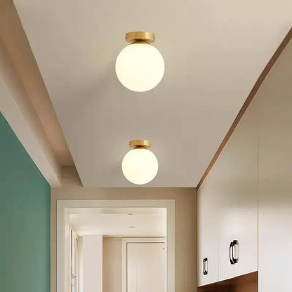 Two decorbites™ modern acrylic ball ceiling lights with spherical frosted glass globes and brass fixtures