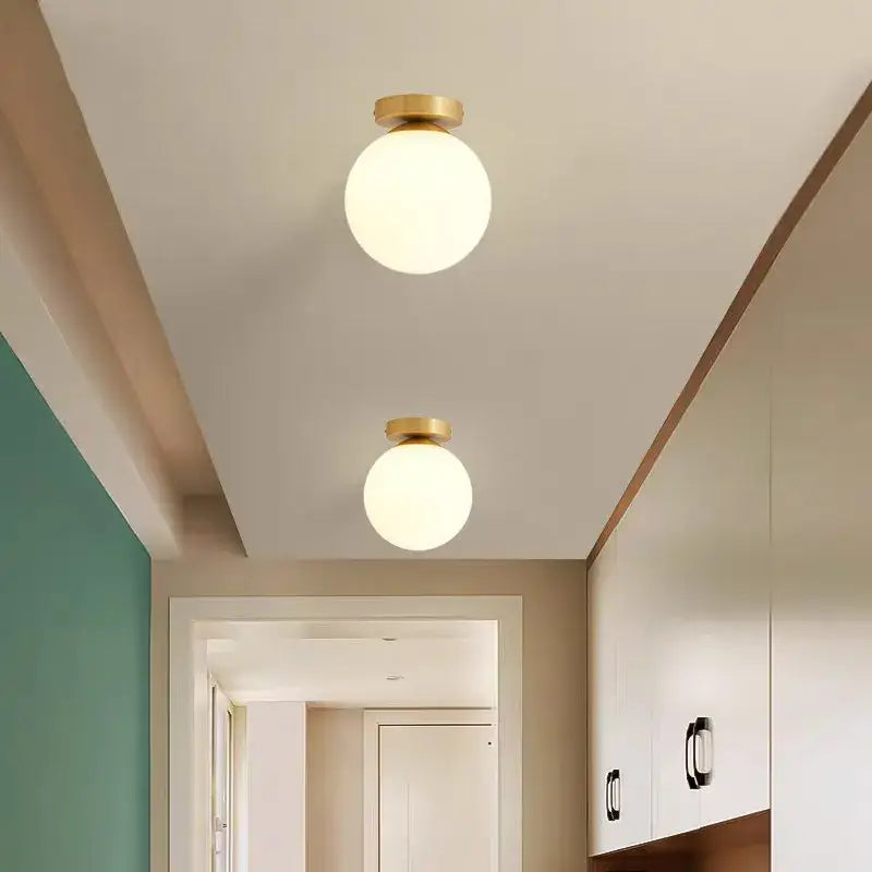 Two decorbites™ modern acrylic ball ceiling lights with spherical frosted glass globes and brass fixtures