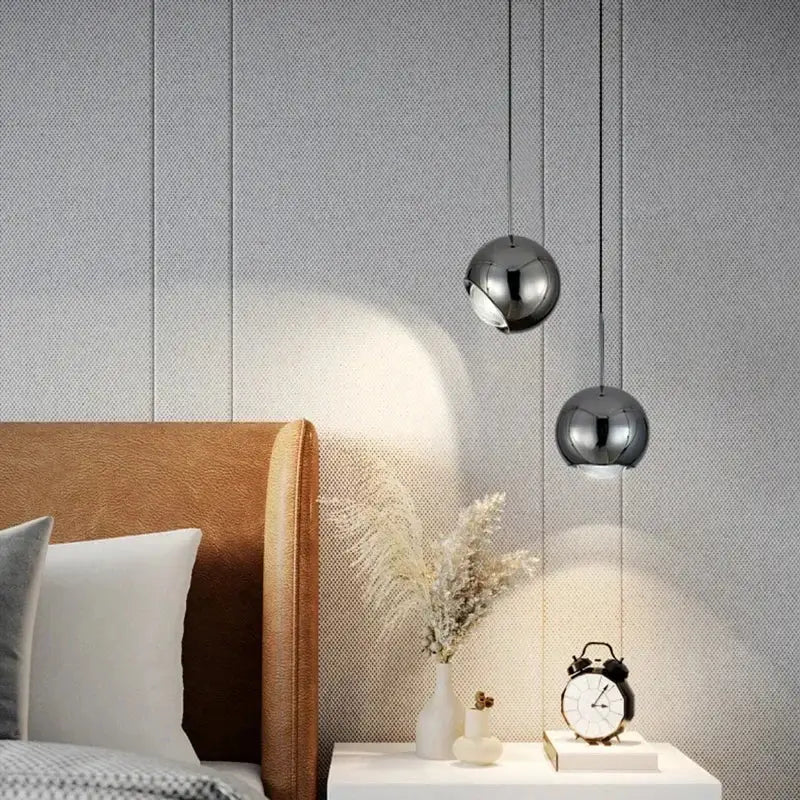 Two chrome-finished spherical decorbites™ modern adjustable led pendant lights hang above a white nightstand