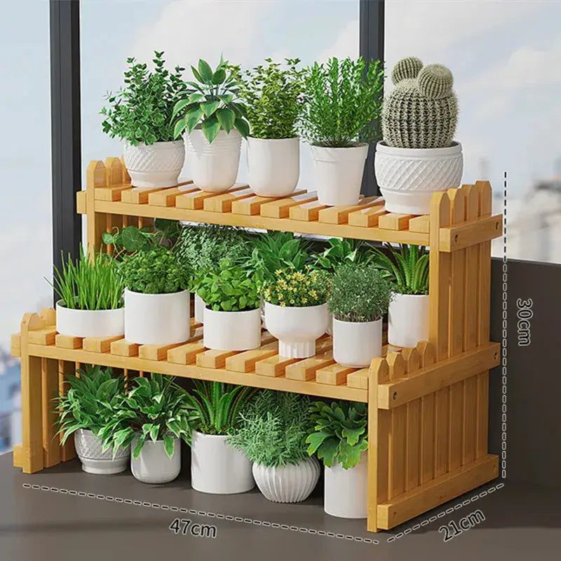 Light brown bamboo 2-tier plant display stand with picket fence design holding white ceramic pots with green plants