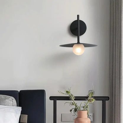 DecorBites™ modern black minimalist bedside wall light with circular base and flat disc shade housing warm bulb
