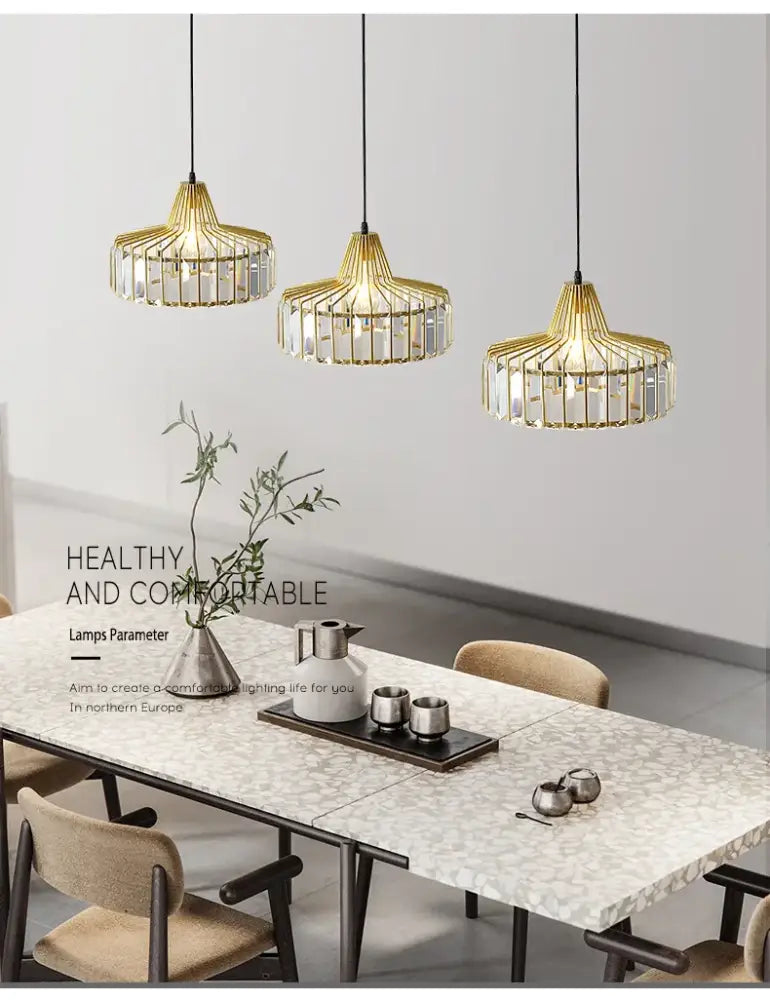 Three elegant gold-toned pendant lamps with crystal glass accents hang above a modern dining table nordic led crystal chandelier