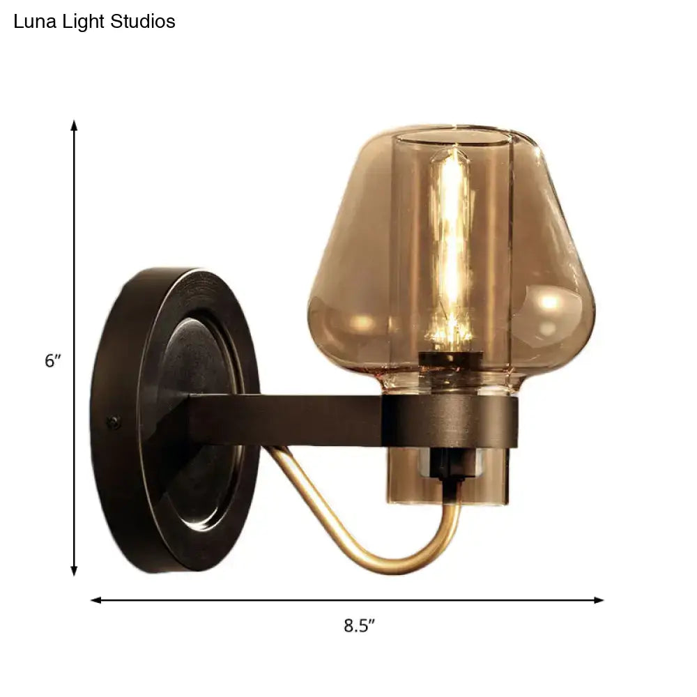 Modern black wall sconce with dark bronze metal base and amber glass shade featuring a visible filament bulb
