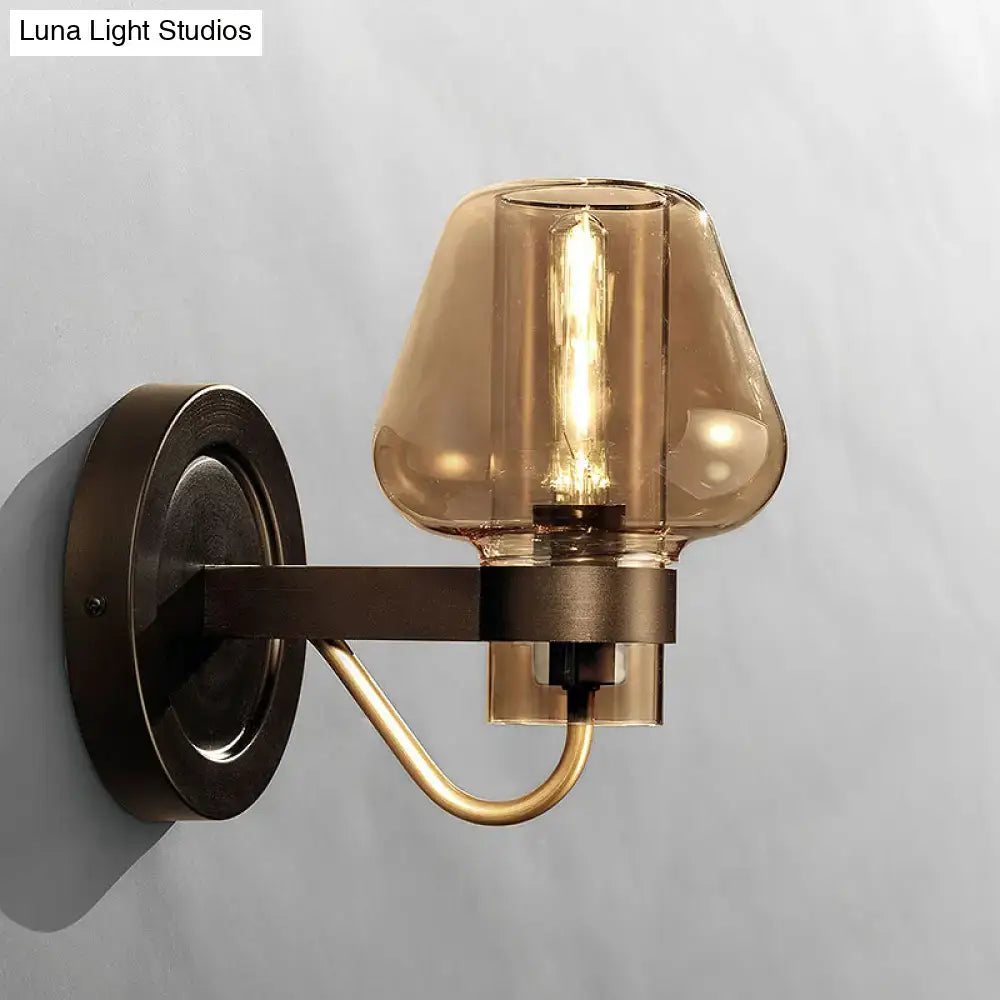 A sleek modern black and brass wall sconce with amber glass shade for bedroom lighting