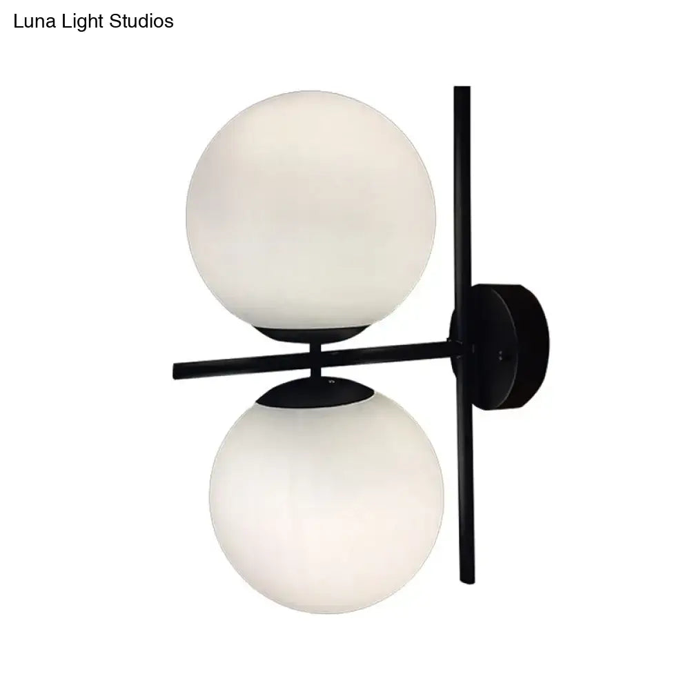 Modern black metal wall light fixture with two frosted white spherical glass shades for living room use
