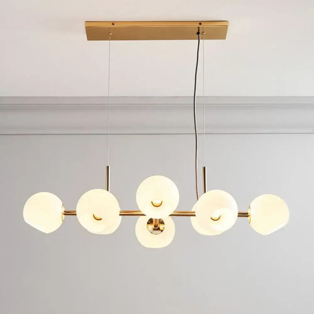 Decorbites modern brass dining room suspension light with six frosted glass orbs in a linear design