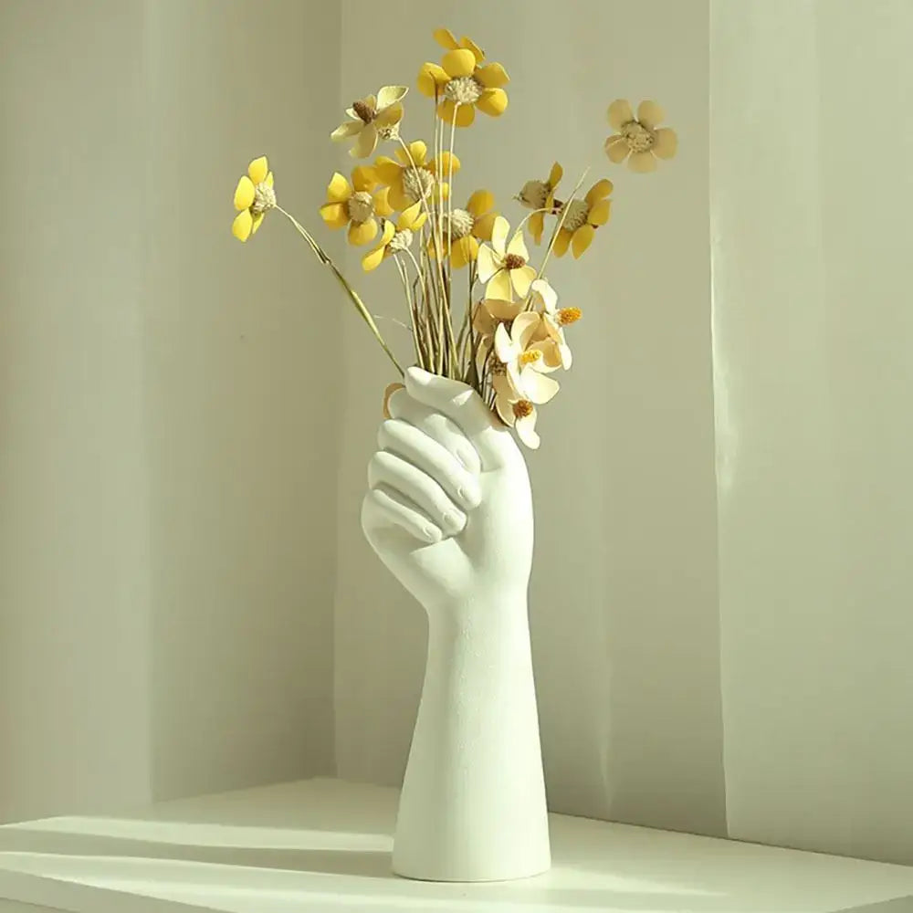 White ceramic arm vase shaped like a hand holding yellow flowers from DecorBites™ modern flower vase collection