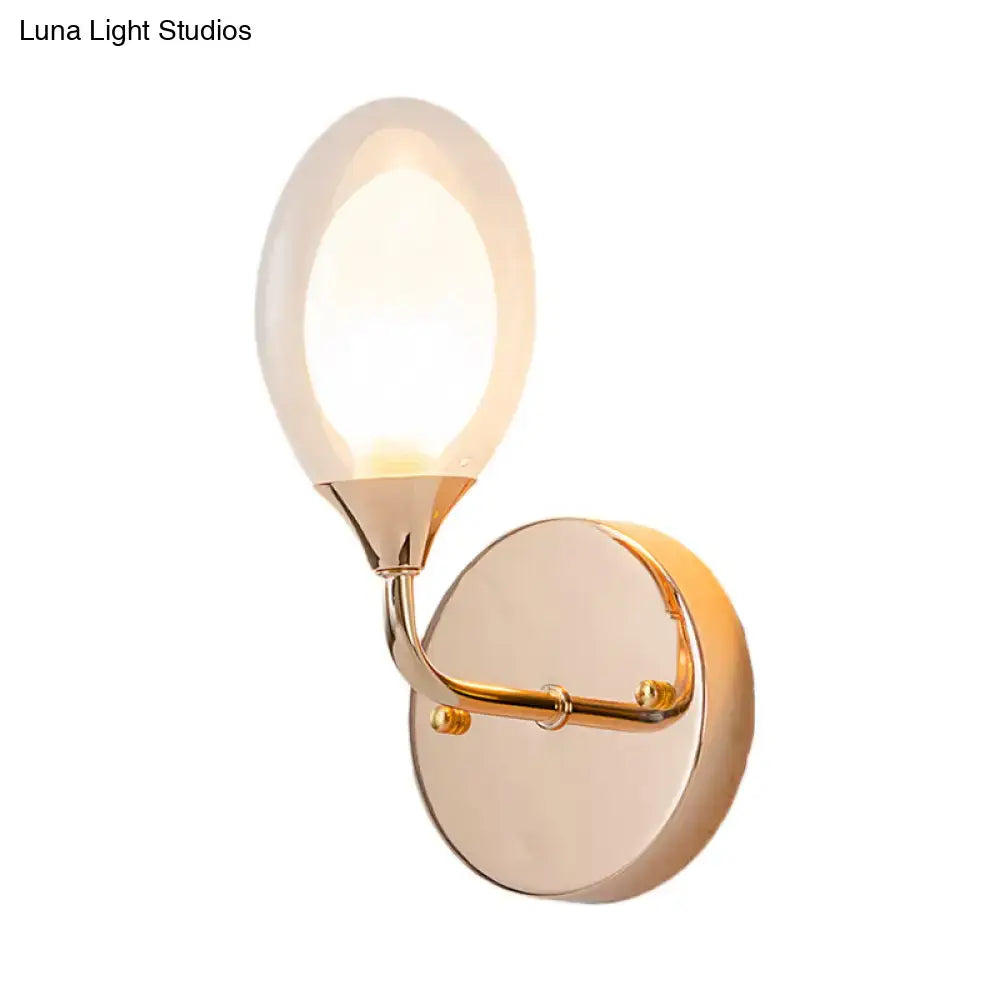 A modern gold wall lamp with an oval frosted glass shade designed as a bedroom wall light fixture