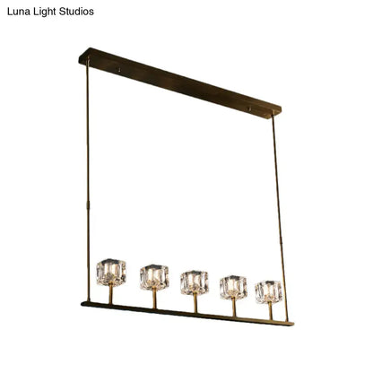 Modern brass-finished rectangular pendant light fixture with five faceted crystal shades for dining area hanging island