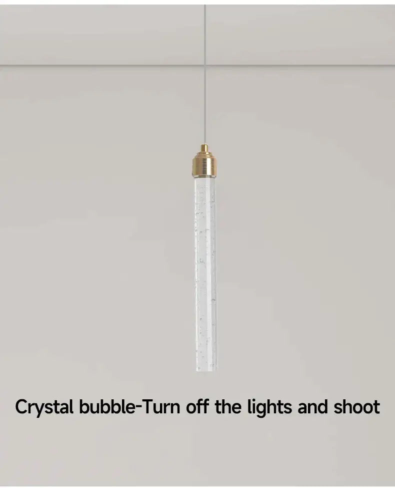 Decorbites modern crystal pendant light featuring a transparent cylinder with gold fixtures and bubble inclusions