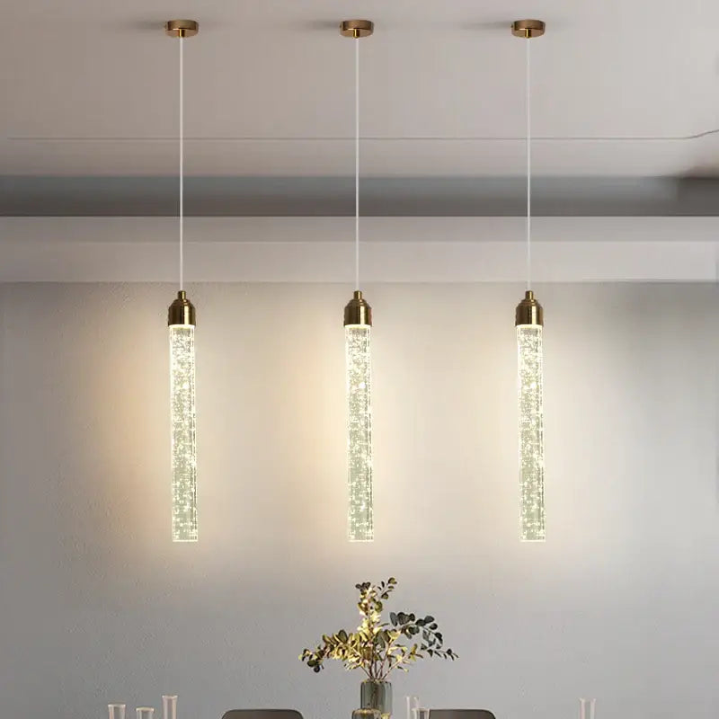 Three elegant gold-toned DecorBites™ crystal pendant lights with sparkling vertical tubes for modern décor