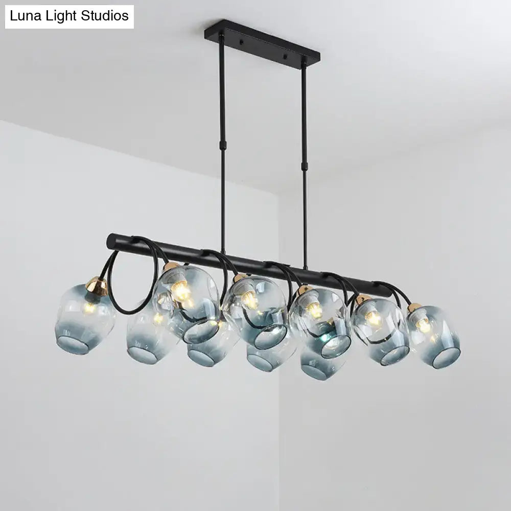 Modern black metal cup island light with six translucent blue glass globe shades and brass accents by DecorBites
