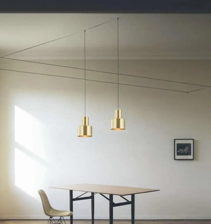Two minimalist brass decorbites™ modern diy pendant lights with cylindrical shades and sleek black cords hanging from ceiling