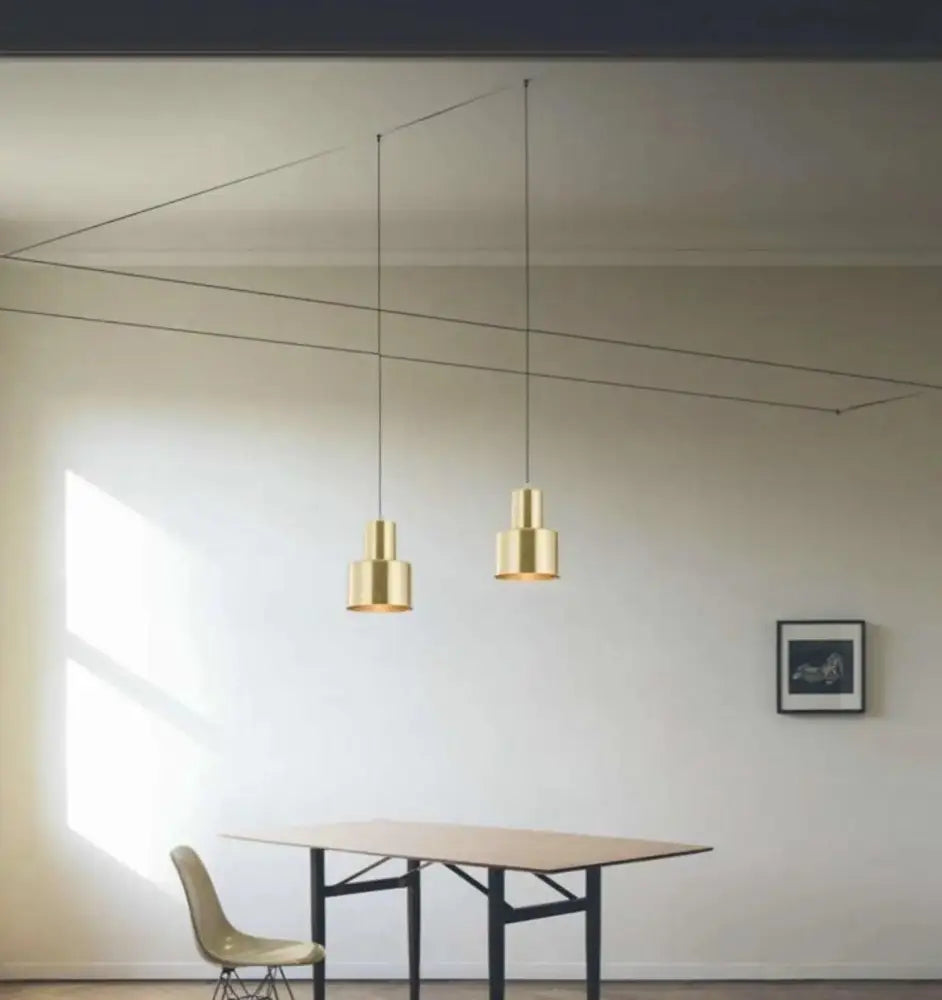 Two minimalist brass decorbites™ modern diy pendant lights with cylindrical shades and sleek black cords hanging from ceiling