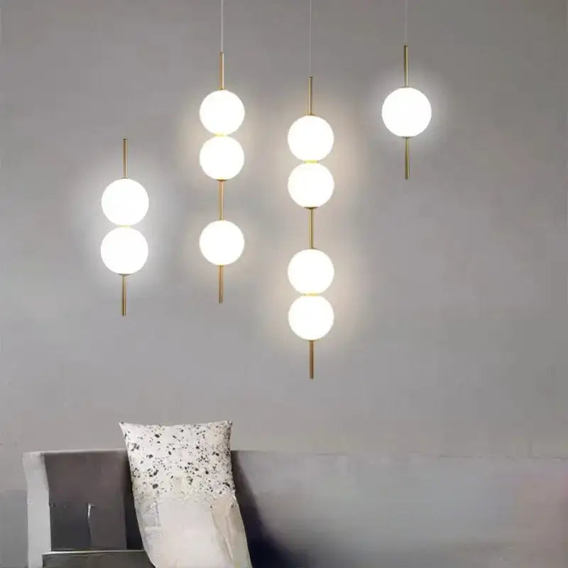 DecorBites™ modern glass pendant lighting with three white spherical glass globes suspended by gold-toned rods