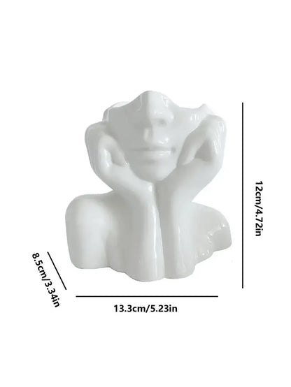 White ceramic human body resin vase shaped as a modern woman bust with hands resting on her cheeks by DecorBites™