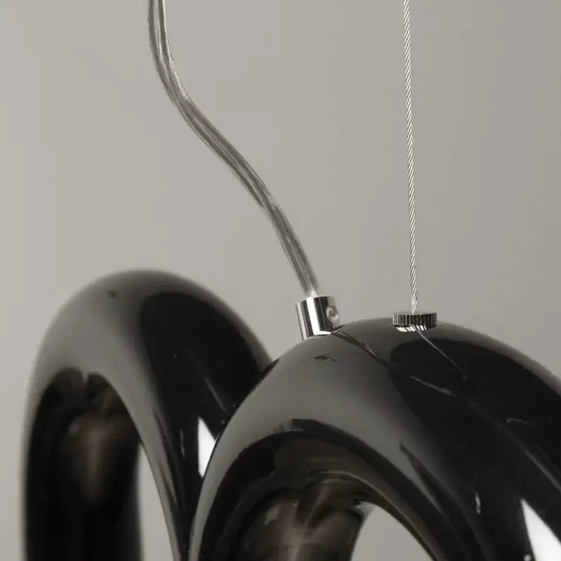 Black glossy resin oblure arch chandelier with sleek curved ring design and metallic suspension hardware by decorbites