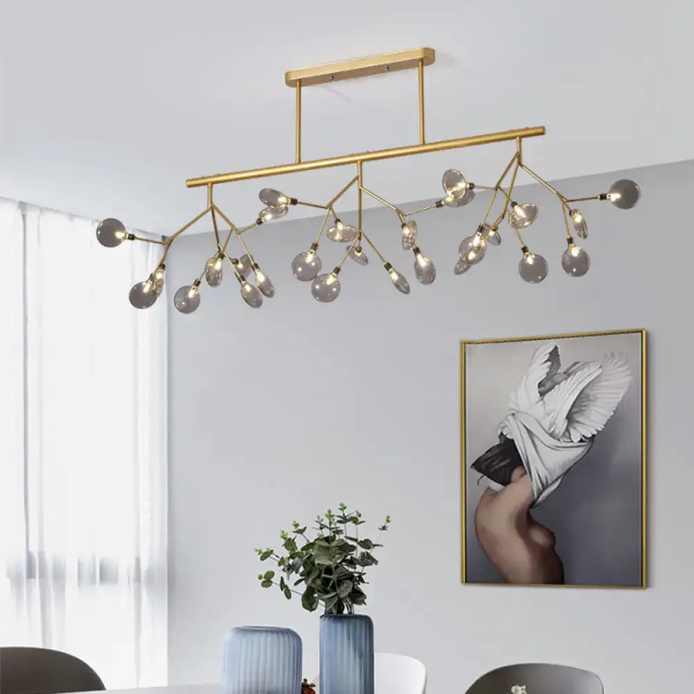 Gold-toned modern metal linear island chandelier with branching arms and frosted glass globe bulbs by DecorBites