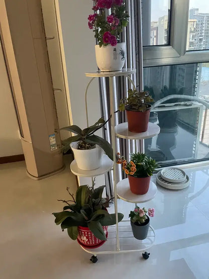 White metal DecorBites™ modern plant stand with four circular shelves and black caster wheels for interior decor