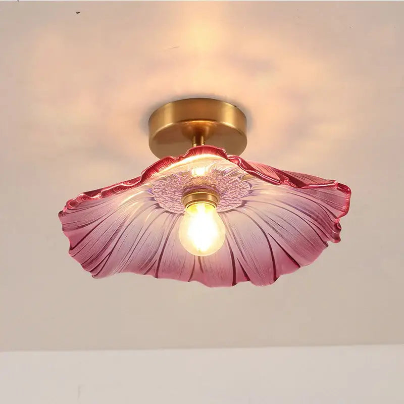 A delicate pink glass flower-shaped modern nordic ceiling light with a brass e27 ceiling fixture and exposed bulb
