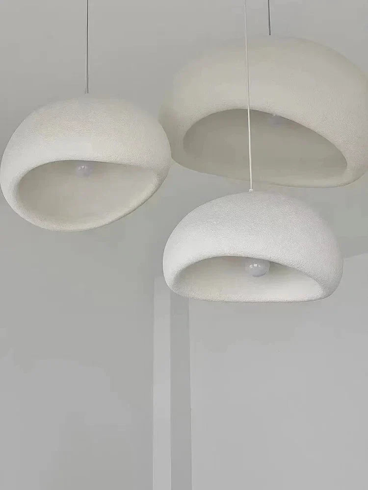 Three minimalist white pendant lights with soft textured domes create warm light in the modern nordic chandelier decorbites