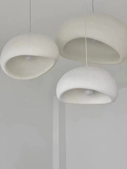 Three minimalist white pendant lights with soft textured domes create warm light in the modern nordic chandelier decorbites