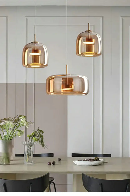 Decorbites modern nordic glass pendant lamp with three amber glass pendant lamps and brass accents above dining table
