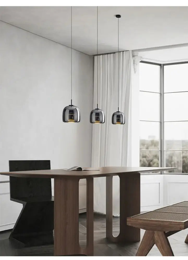 Three sleek metallic decorbites™ modern nordic glass pendant lamps hang above a dining table as glass restaurant pendant lights