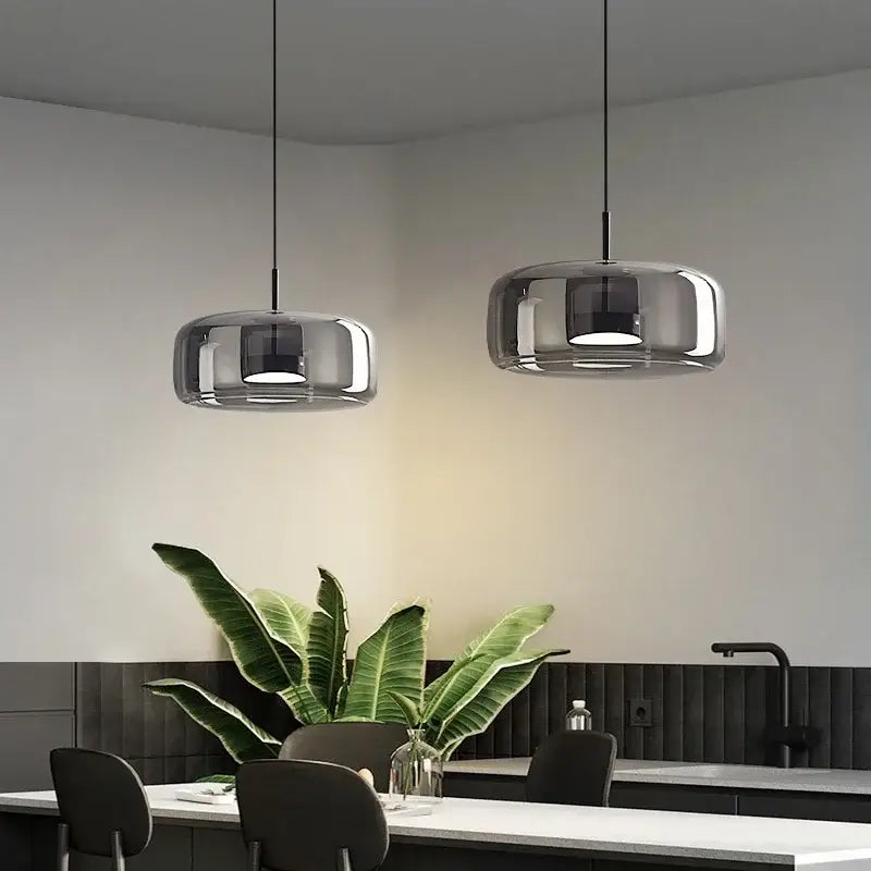 Two sleek decorbites™ modern nordic glass pendant lamps with chrome finish and rounded shades hanging from black cords