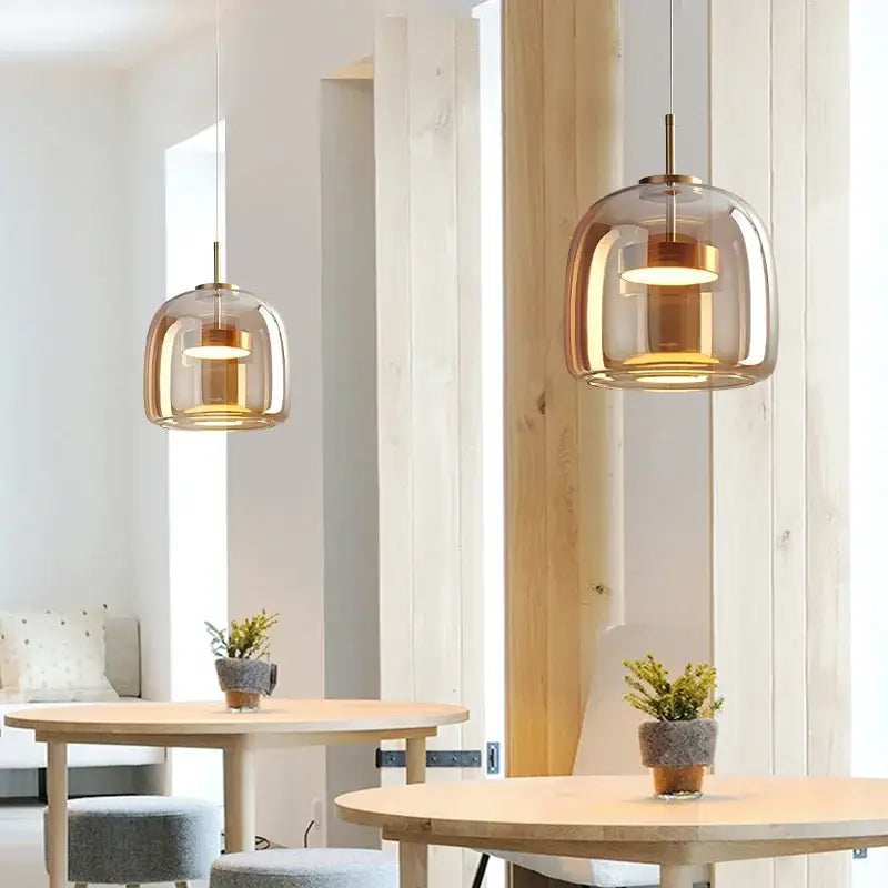 Warm-toned nordic glass pendant lamp with brass accents hanging above wooden tables as a stylish glass restaurant pendant