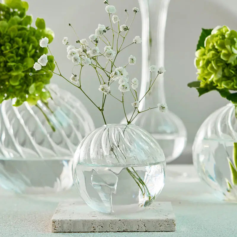 Clear glass spherical vase with ribbed texture holding white baby’s breath flowers from decorbites modern nordic set
