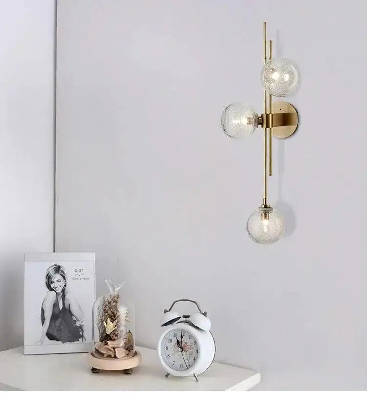 Gold-toned wall sconce with three clear textured glass globes in DecorBites™ modern Nordic glass wall sconce by Adabella